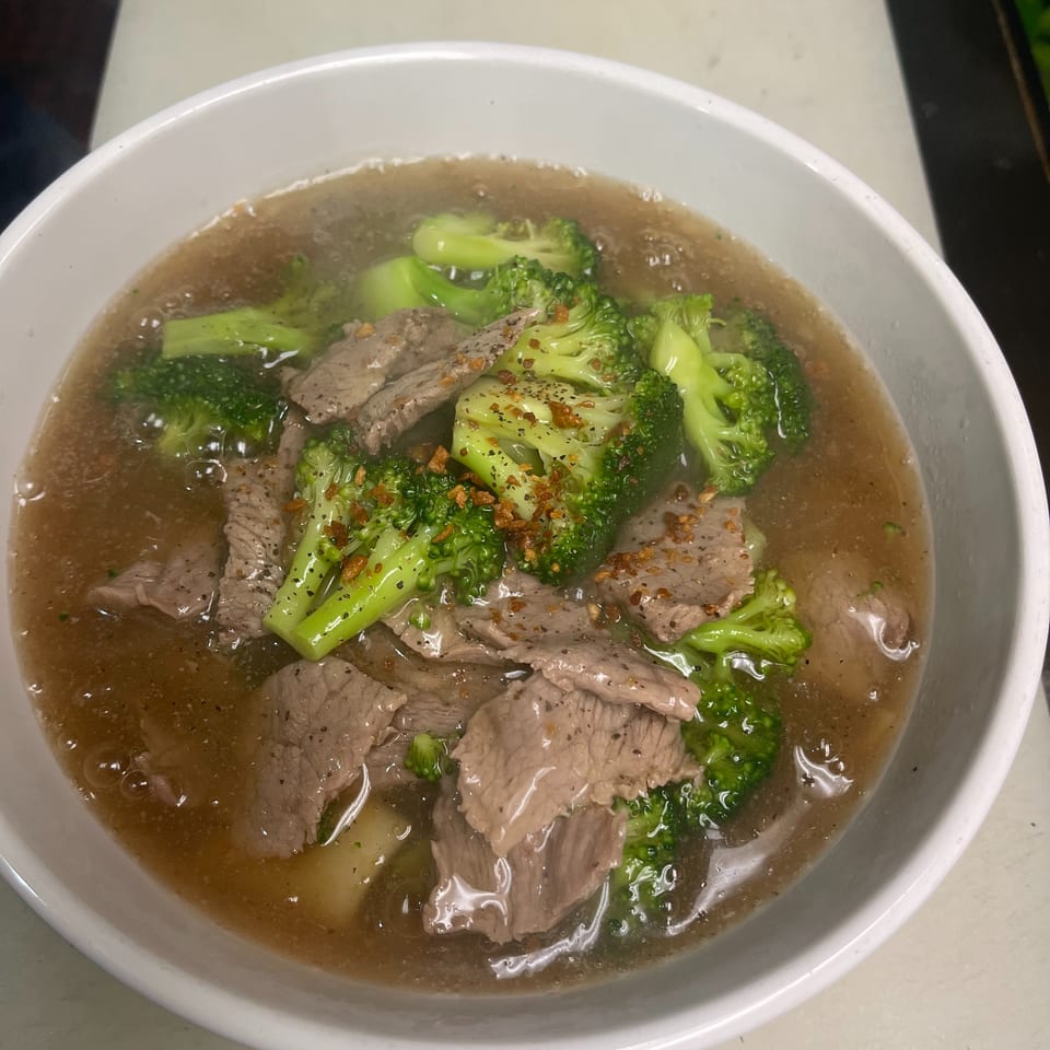 Beef and broccoli in a savory broth, garnished with fried garlic and black pepper.